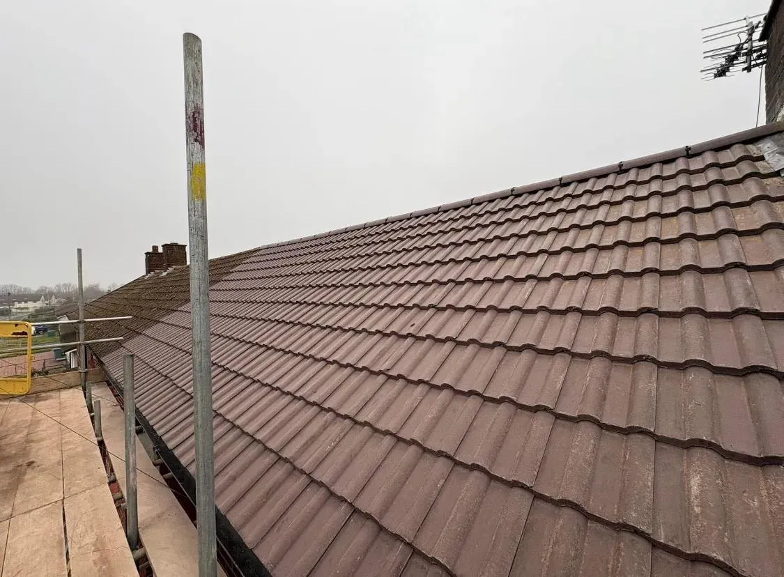 Newly installed or re-tiled pitched roof with brown concrete tiles and scaffolding.