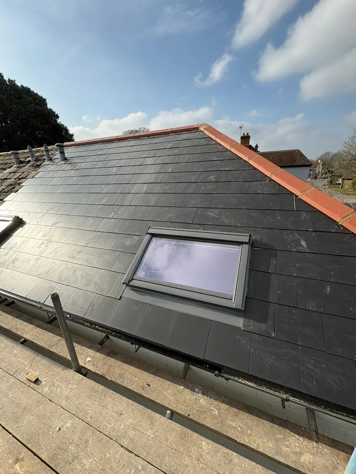 New slate roof installation with Velux window and scaffolding on a home in Devon or Cornwall.