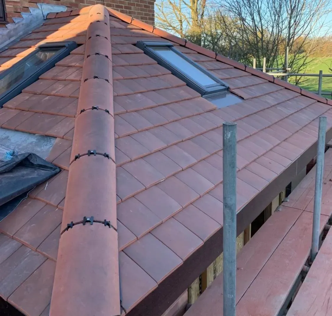 Completed warm roof conservatory conversion with terracotta roof tiles and Velux windows