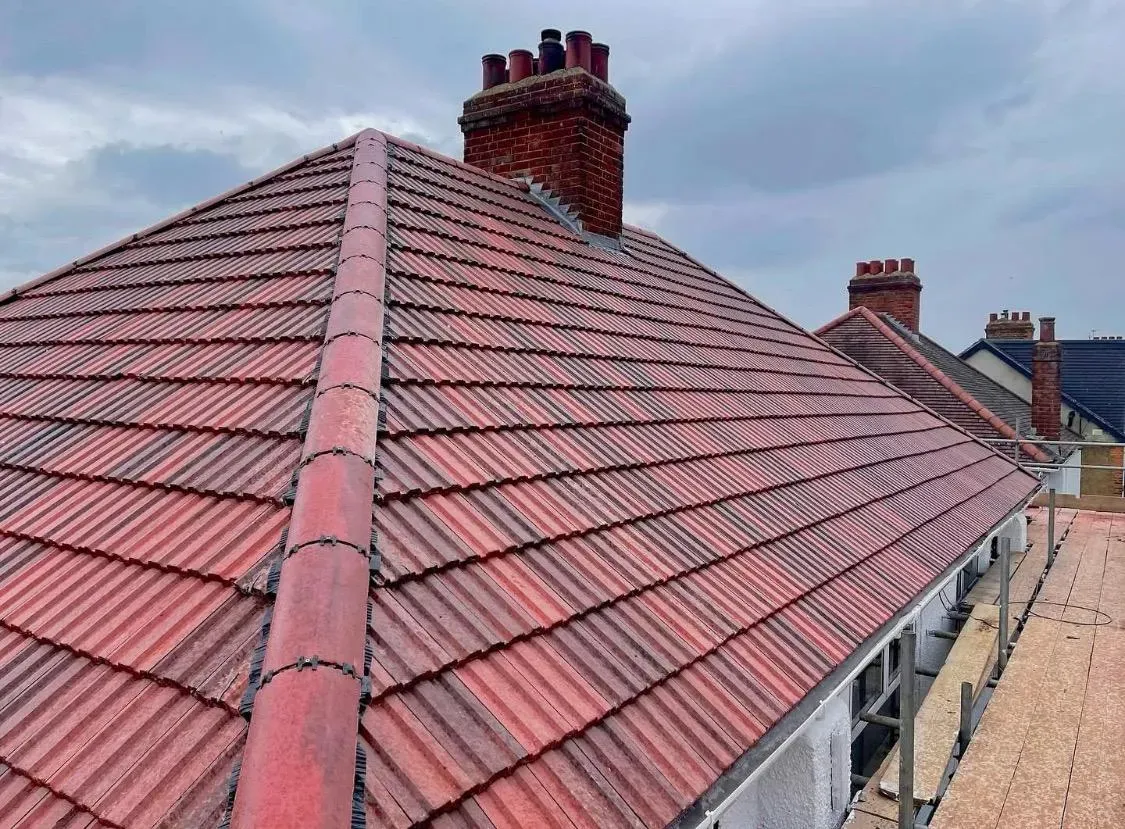 Newly fitted red tile roof with dry-fix ridge system and chimneys, showcasing a complete re-roof installation in Devon or Cornwall.